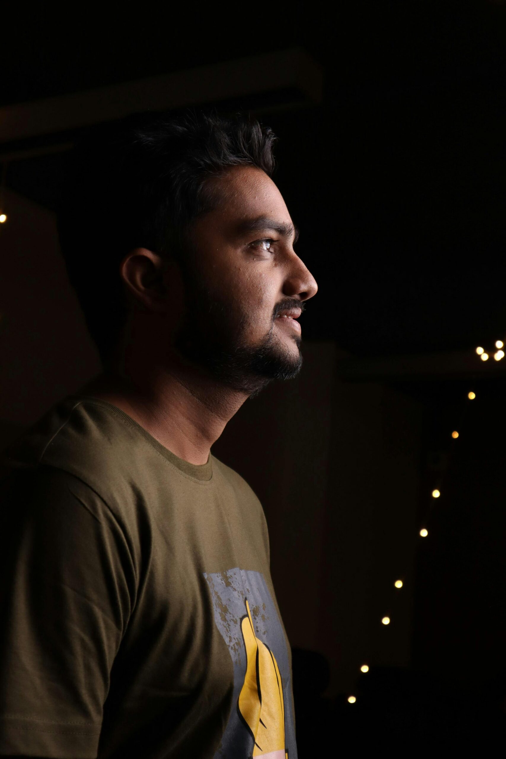 Casual portrait of a smiling south Asian man in Bengaluru with a bearded side profile.